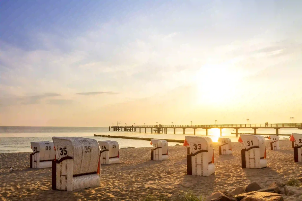 Perfekter Ostsee Urlaub mit Hund: Die besten Tipps und Tricks 5 Strandkörbe am Ostseestrand bei Sonnenuntergang mit Blick auf eine Seebrücke, ideal für einen erholsamen Aufenthalt mit Hund an der Küste.