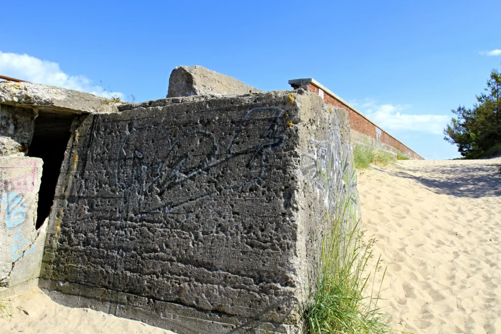 Urlaub mit Hund in Prora auf Rügen – Der perfekte Guide 8 Verwitterter Betonbunker mit Graffiti in Dünenlandschaft unter blauem Himmel, Teil der historischen Prora auf Rügen.