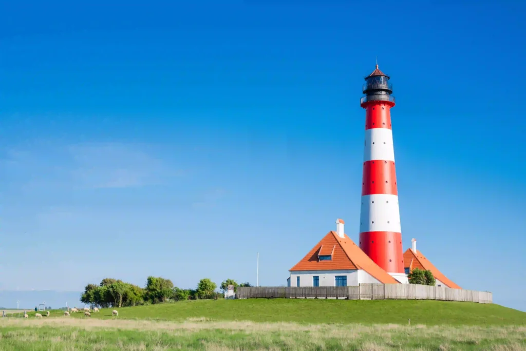 Urlaub mit Hund in St. Peter-Ording: Dein kompletter Guide für entspannte Ferien 1 Der rot-weiß gestreifte Leuchtturm Westerhever auf einer grünen Anhöhe, ein Wahrzeichen nahe St. Peter-Ording.