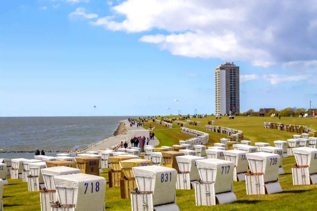 Büsum mit Hund: Perfekter Nordsee-Urlaub mit Vierbeiner 7 Zahlreiche Strandkörbe entlang des Deichs in Büsum mit dem Büsumer Hochhaus im Hintergrund, ein beliebter Ort für Besucher und ideal für Spaziergänge mit Hund in Büsum.