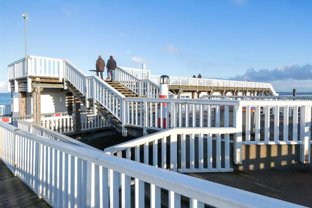 Cuxhaven mit Hund entdecken - Ferienideen für Hundebesitzer 9 Helle Holzstege und Geländer einer Seebrücke in Cuxhaven mit Blick auf das Wasser, ideal für einen Ausflug mit Hund an der Küste.