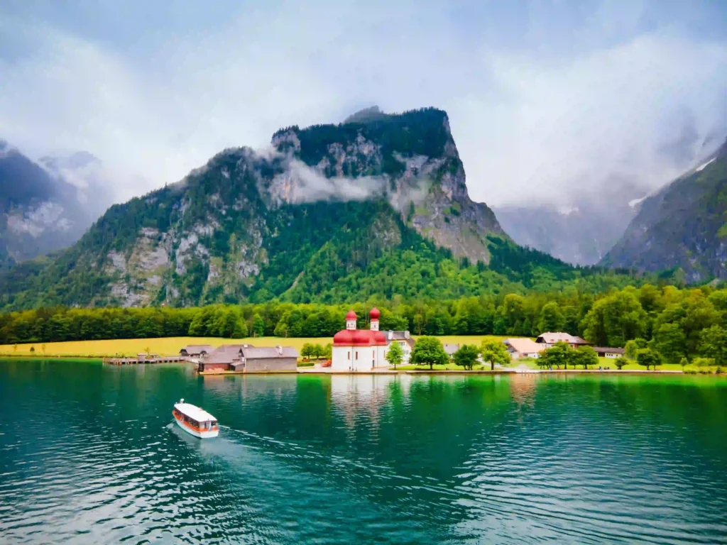 Urlaub am Königssee mit Hund: Tipps & Highlights 2 Panorama vom Königssee mit Hund, ruhigem Wasser, weißer Kirche mit roten Kuppeln und Bergen im Hintergrund