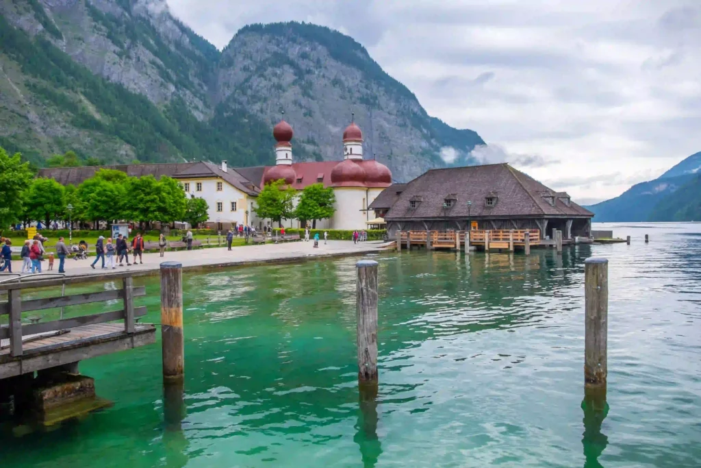 Urlaub am Königssee mit Hund: Tipps & Highlights 3 St. Bartholomä am Königssee mit Hund, grüne Berge, Boathouse und klarer See mit Holzstegen und Spaziergängern am Ufer