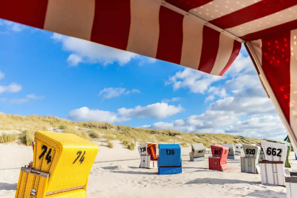 Langeoog mit Hund: dein Perfekter Inselurlaub mit Vierbeiner 4 Nahaufnahme von Strandkörben am Langeooger Strand mit Dünen im Hintergrund, genießen Sie den Strandurlaub auf Langeoog mit Hund.