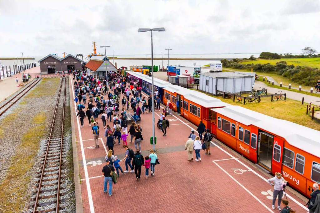 Langeoog mit Hund: dein Perfekter Inselurlaub mit Vierbeiner 8 Ankunft am Bahnhof Langeoog mit vielen Menschen, die aus der Inselbahn steigen, perfekt für die Anreise nach Langeoog mit Hund.