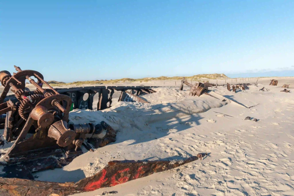 Norderney mit Hund: Top Wanderungen & Ausflugsziele an der Nordsee 5 Rohe, rostige Schiffswrackteile liegen im Sand am Strand von Norderney, teilweise vom Wind freigelegt – ein faszinierendes Relikt, das man bei einem Strandspaziergang mit Hund entdecken kann.