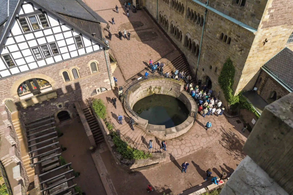 Wartburg mit Hund: Dein perfekter Wanderurlaub im Thüringer Wald 6 Luftaufnahme des Innenhofs der Wartburg mit dem Brunnen und Besuchern, ein beliebter Ort nach dem Wandern.