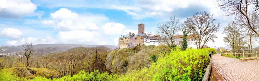 Wartburg mit Hund: Dein perfekter Wanderurlaub im Thüringer Wald 1 Panoramablick auf die Wartburg von einem Wanderweg aus, umgeben von grüner Natur, einladend zum Wandern und Entdecken.