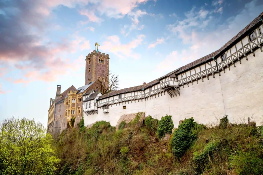 Wartburg mit Hund: Dein perfekter Wanderurlaub im Thüringer Wald 9 Seitenansicht der Wartburg mit langer Mauer und dem Bergfried vor einem bewölkten Himmel, toll für eine Tour beim Wandern zur Wartburg.
