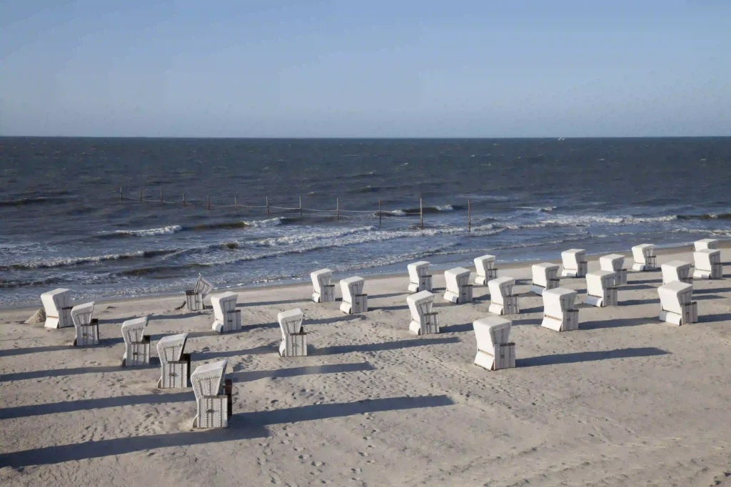 Urlaub auf Wangerooge mit Hund: Dein Guide für perfekte Ferien mit Vierbeiner 7 Reihen von Strandkörben am weiten Sandstrand von Wangerooge mit Blick auf die Nordsee, hundefreundlicher Bereich in der Ferne.