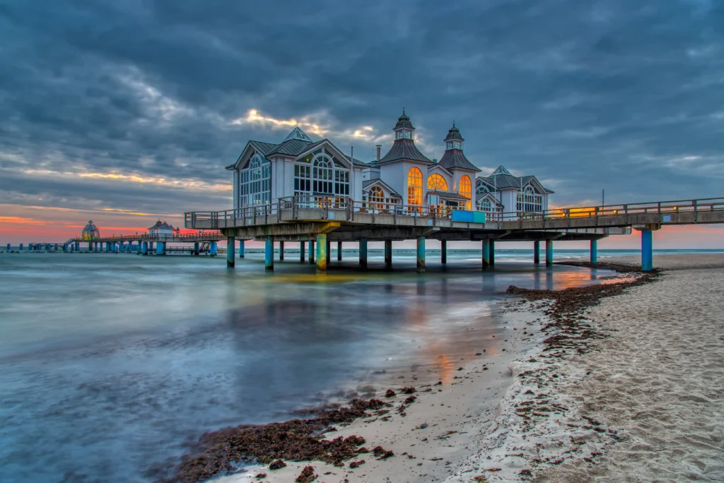 Urlaub mit Hund in Sellin auf Rügen – Dein perfekter Ostsee-Guide 4 Küstenlandschaft mit bewaldeten Klippen, Strand und ruhigem Wasser bei Sellin auf Rügen unter teils bewölktem Himmel