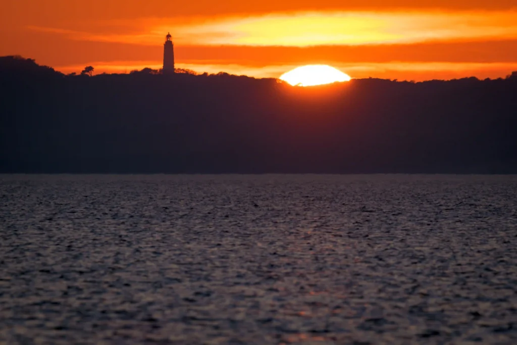 Hiddensee mit Hund: Perfekter Guide für deinen Inselurlaub 14 Dramatischer Sonnenuntergang über Wasser mit Leuchtturm und Küste – perfektes Motiv für Urlaub auf Hiddensee.
