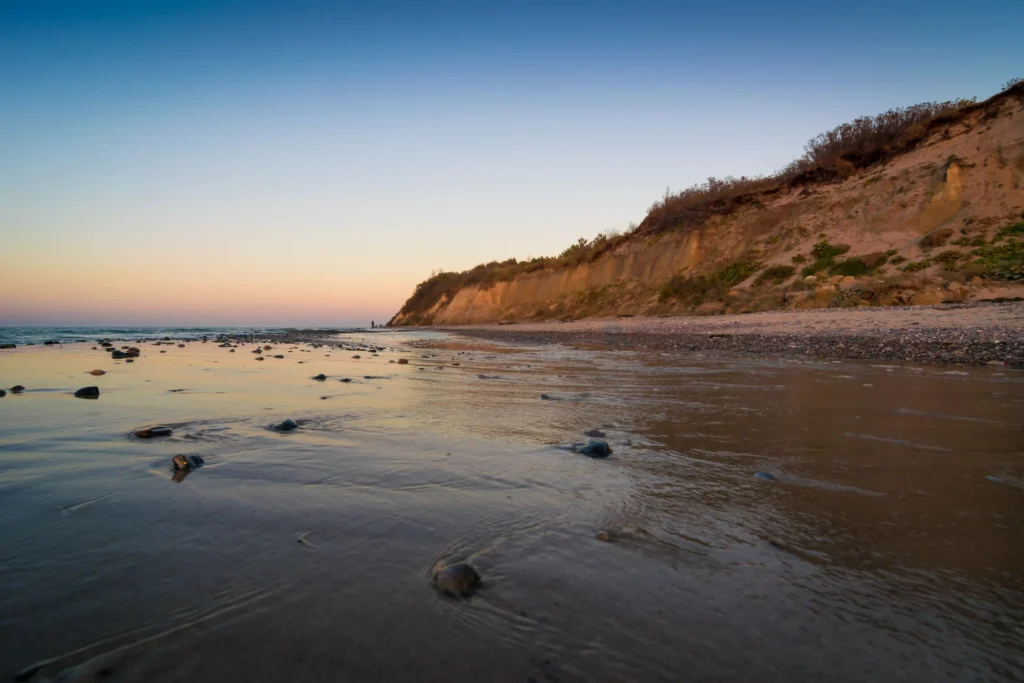 Dranske Ausflugsziele: Perfekter Urlaub mit Hund auf Rügen 7 Sonnenaufgang über dem ruhigen Strand von Dranske mit Klippen, Kieselsteinen und sanften Wellen am Meerufer.