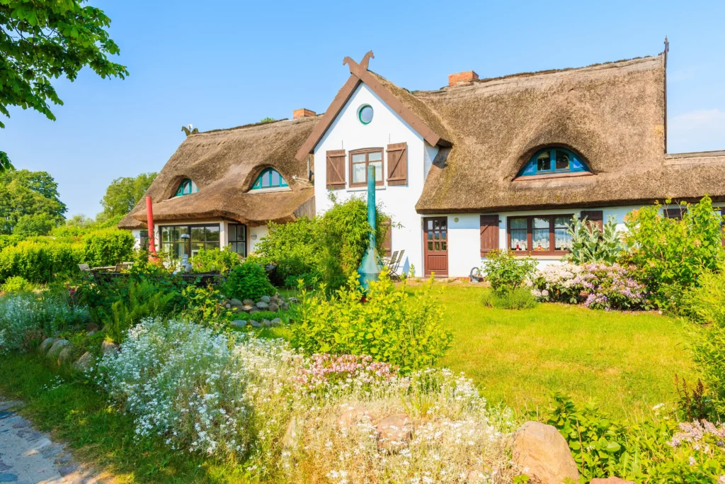 Urlaub mit Hund in Sellin auf Rügen – Dein perfekter Ostsee-Guide 8 Traditionelles Haus mit Reetdach und grüner Naturkulisse bei Sellin auf Rügen unter klarem blauem Himmel
