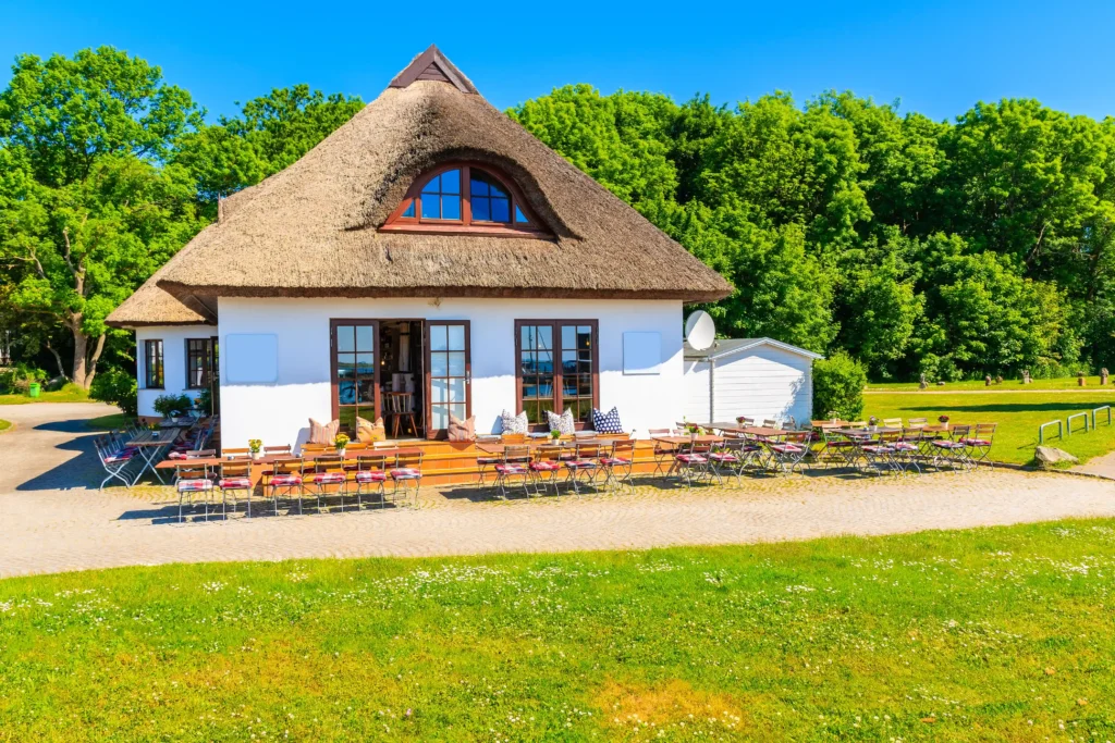 Hiddensee mit Hund: Perfekter Guide für deinen Inselurlaub 3 Charmantes reetgedecktes Café mit Außenbereich an sonnigem Tag, ideal für Urlaub auf Hiddensee genießen.