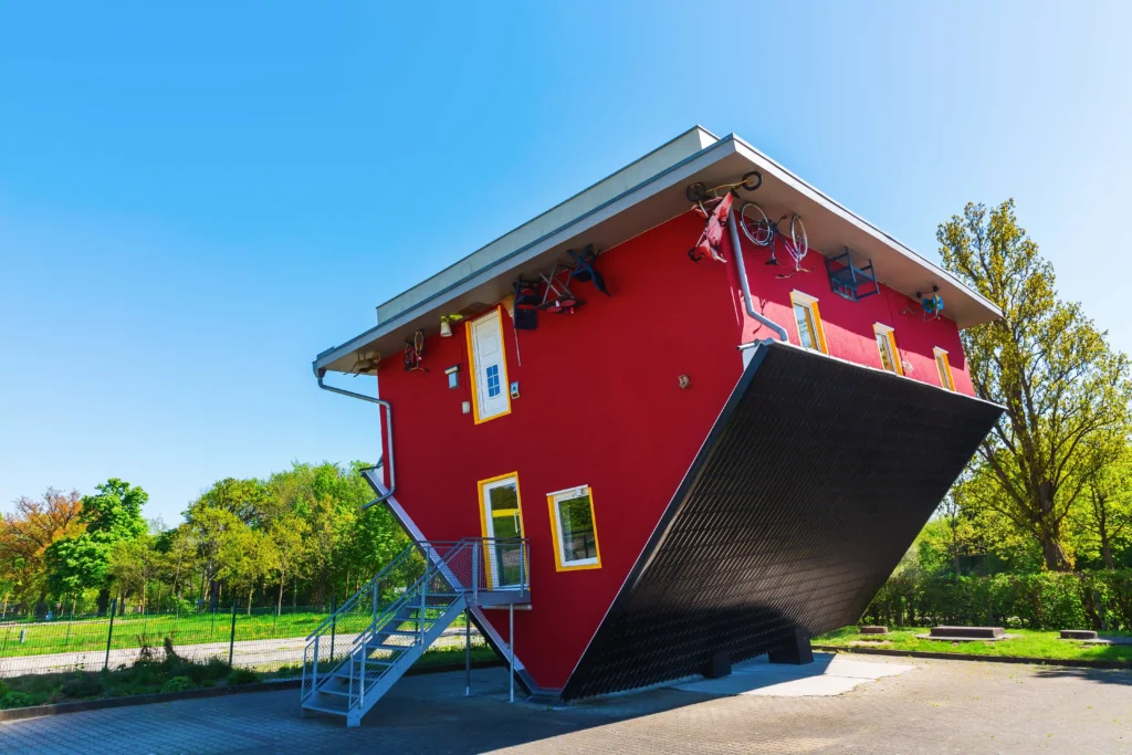 Urlaub in Putbus mit Hund – Der perfekte Guide für Rügen 10 Ein rotes, auf dem Kopf stehendes Haus mit Treppe, Fenstern und Fahrrad, einzigartiges Bauwerk in Putbus.