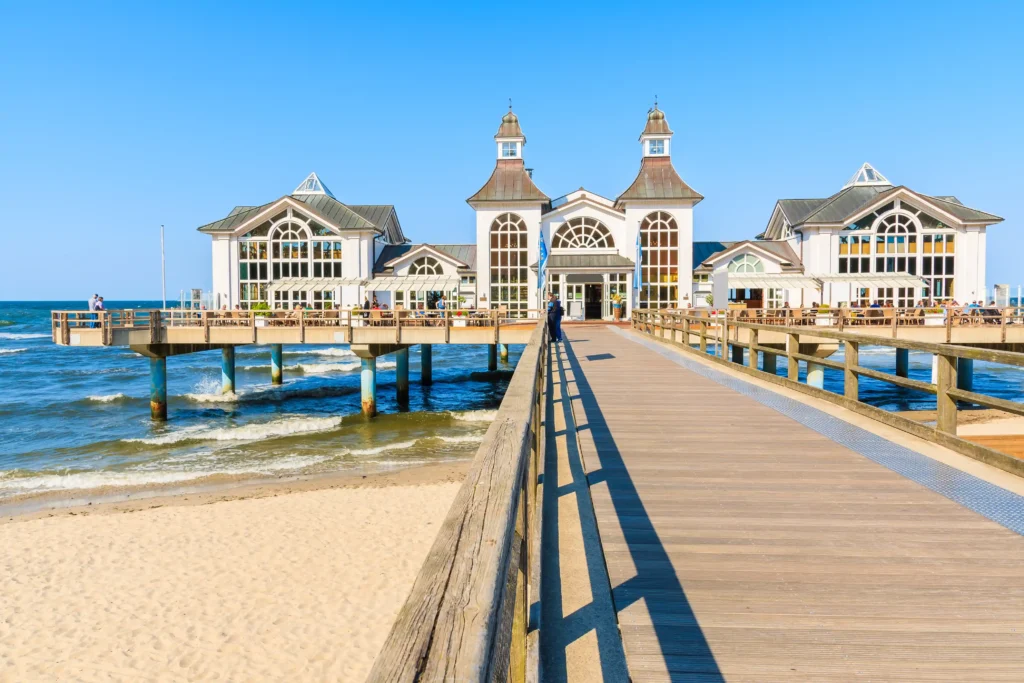 Urlaub mit Hund in Sellin auf Rügen – Dein perfekter Ostsee-Guide 3 Küstenlandschaft mit bewaldeten Klippen, Strand und ruhigem Wasser bei Sellin auf Rügen unter teils bewölktem Himmel