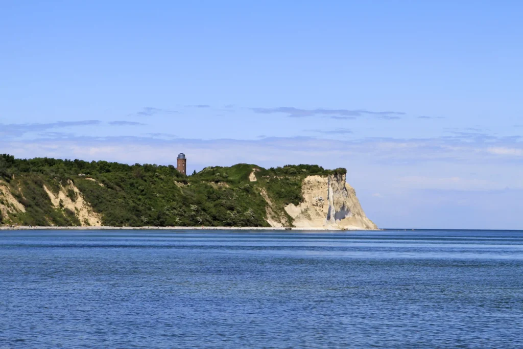 Ausflug Kap Arkona mit Hund: Dein kompletter Guide für Rügen 2 Kap Arkona zeigt Leuchtturm auf grünem Hügel, weiße Kreidefelsen und ruhiges Meer unter klarem blauem Himmel.