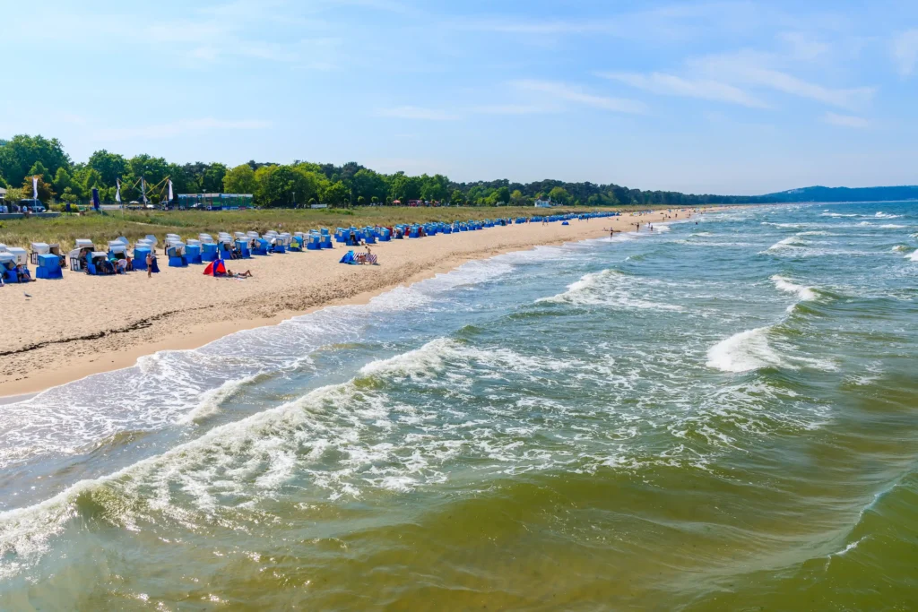 Urlaub Göhren mit Hund: Perfekte Ferien auf Rügen 2 Sonniger Strand mit blauen Strandkörben, Menschen und Wellen am Meer bei Göhren auf Rügen an einem Sommertag