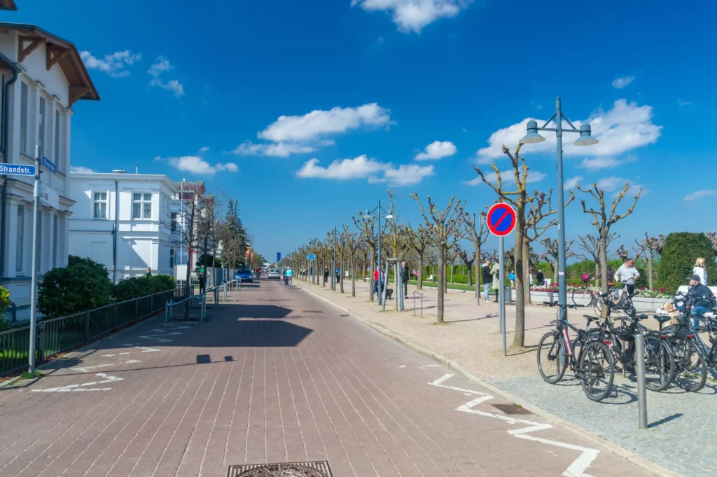 Urlaub mit Hund in Heringsdorf: Dein perfekter Ostsee-Guide 17 Lebhafte Straßenansicht in Heringsdorf an der Ostsee mit Radweg, historischen Gebäuden und Spaziergängern an sonnigem Tag