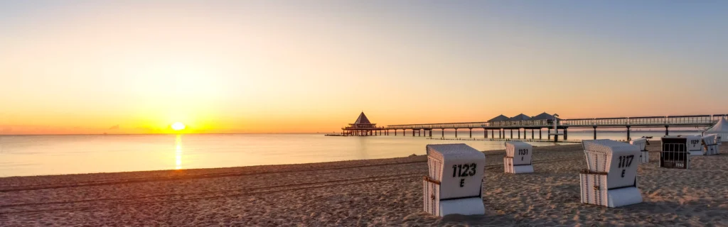 Urlaub mit Hund in Heringsdorf: Dein perfekter Ostsee-Guide 20 Sonnenaufgang über Strand mit Strandkörben, Pier und ruhigem Meer in Heringsdorf mit Hund am Ostseestrand