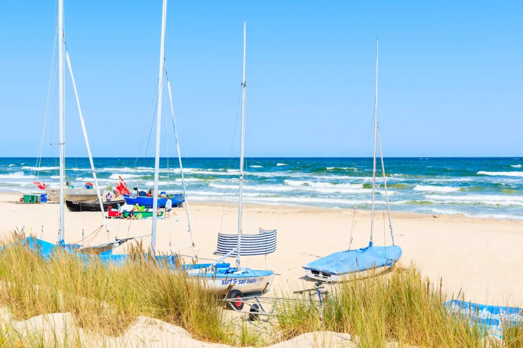 Urlaub mit Hund in Baabe auf Rügen: Top Tipps & Guide 10 Strand mit Booten, Menschen und Dünen unter blauem Himmel am sonnigen Küstenabschnitt Baabe Rügen