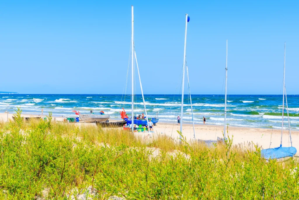 Urlaub mit Hund in Baabe auf Rügen: Top Tipps & Guide 6 Sonniger Strand mit Booten, Dünen und Menschen am Wasser in Baabe Rügen, klarer Himmel und blaues Meer im Hintergrund