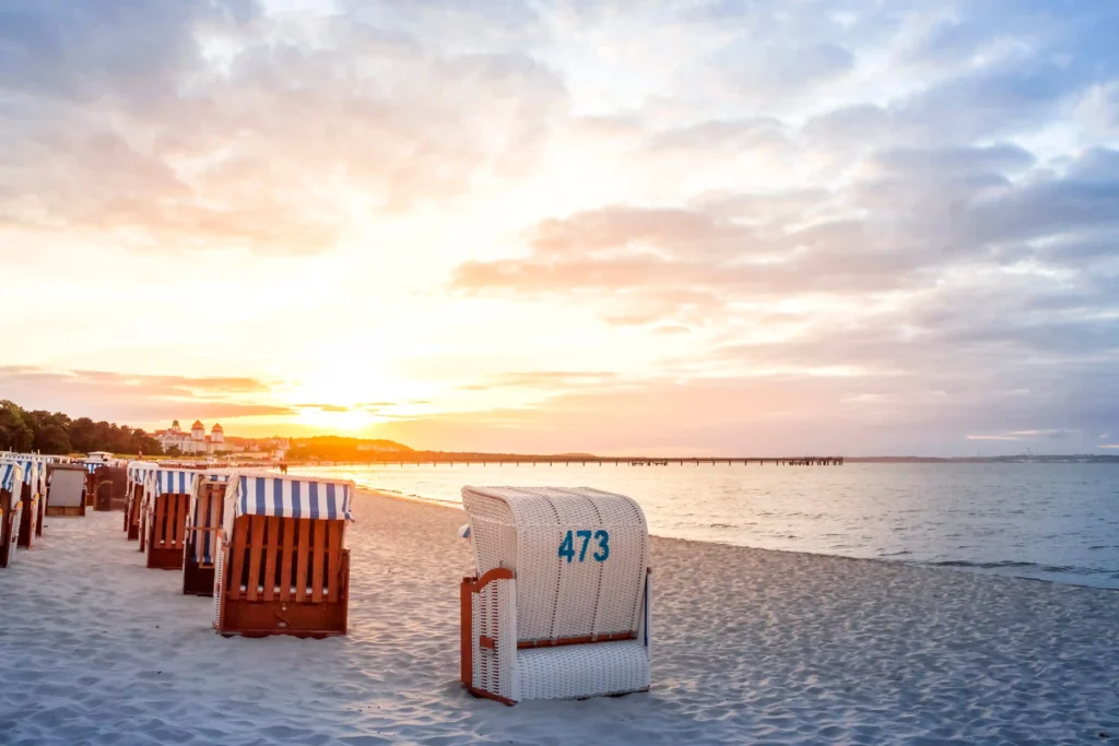 Dein perfekter Ausflug zum Hundestrand Binz 9 Strandpanorama von Binz mit Sand, Menschen, Pier, Gebäuden mit roten Dächern und bewölktem Himmel im Hintergrund