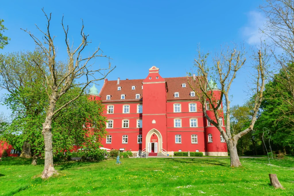 Glowe auf Rügen: Perfekter Urlaub mit Hund 3 Rotes Schlosshotel Spoyler mit grünem Rasen und Skulpturen bei klarem Himmel – perfekter urlaug in glowe rügen.