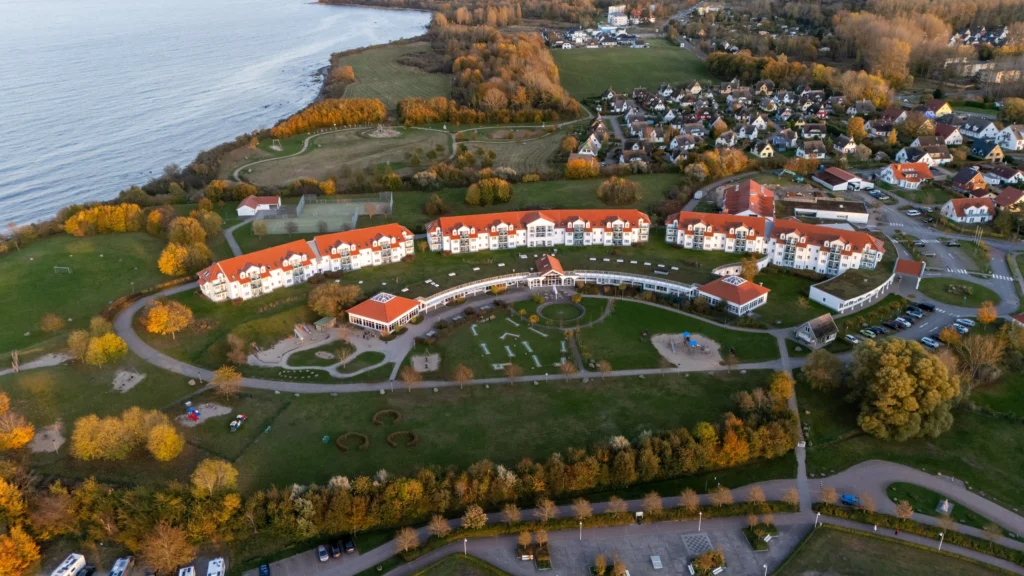 Glowe auf Rügen: Perfekter Urlaub mit Hund 2 Luftaufnahme eines herbstlichen Küstenresorts mit Strand, Grünflächen und Häusern für urlaug in glowe rügen