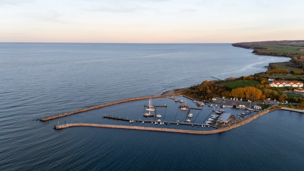 Glowe auf Rügen: Perfekter Urlaub mit Hund 4 Luftaufnahme eines ruhigen Hafens mit Segelbooten und herbstlicher Küstenlandschaft beim urlaug in glowe rügen.