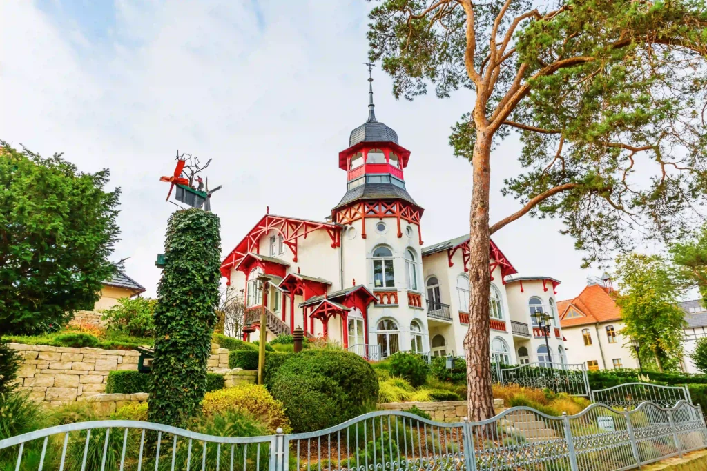 Urlaub mit Hund in Zinnowitz: Dein perfekter Ostseeurlaub 8 Weißes historisches Gebäude mit roten Akzenten und Garten in Zinnowitz mit Hund, ideal für Urlaub und Spaziergänge.
